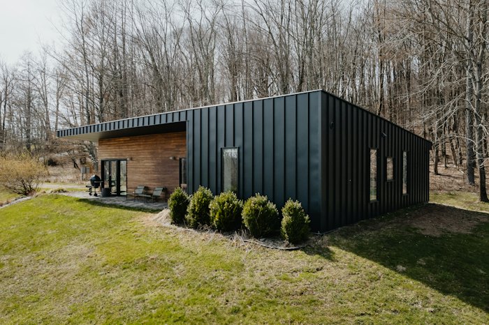 Black cabin clad in vertical standing-seam metal siding