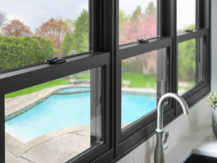 Black-framed double-hung windows above a kitchen sink, looking out onto a backyard pool